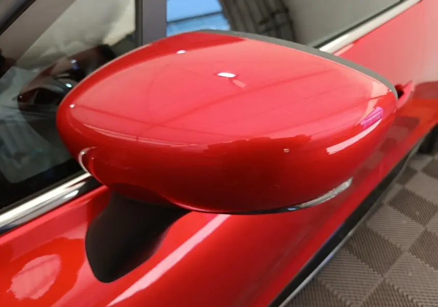 Rétroviseur droit rouge vif de Renault Clio Intens 2018, vue rapprochée sur la portière et la carrosserie brillante.