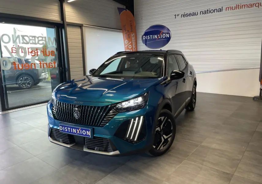 Peugeot 2008 bleu 3/4 avant droit en showroom, avec calandre noire et feux LED à griffes distinctifs.