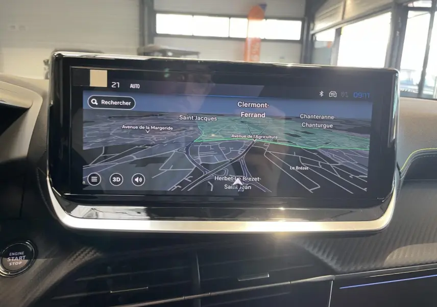 Vue intérieure centrée sur l'écran tactile de navigation 3D du Peugeot 2008 hybride, avec tableau de bord noir et surpiqûres jaunes.