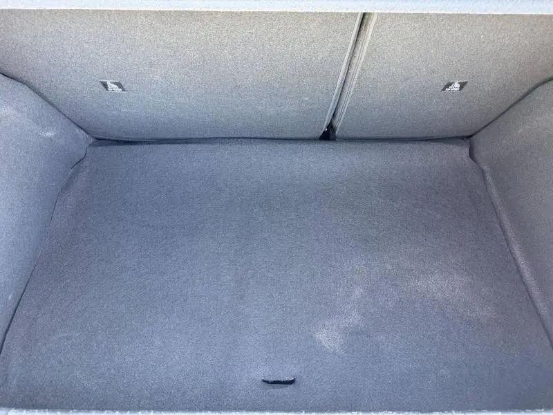 Vue intérieure du coffre vide de la Peugeot 208 1.2 100ch Allure, revêtement tissu gris uniforme.