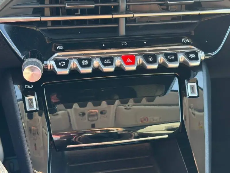 Vue rapprochée de la console centrale noire brillante de la Peugeot 208 avec boutons de commande et écran tactile éteint.