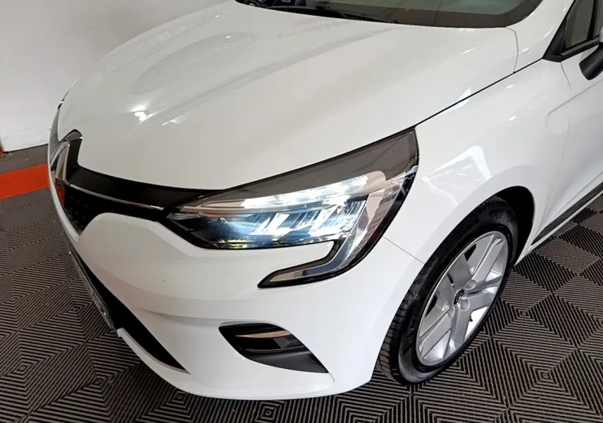 Vue 3/4 avant droit d'une Renault Clio Business blanche mettant en valeur ses phares LED et sa calandre noire brillante.