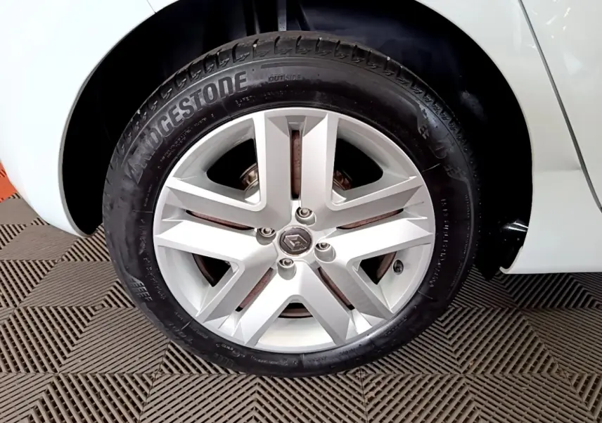 Gros plan sur la roue arrière droite d'une Renault Clio blanche 2021, avec partie de la carrosserie visible.