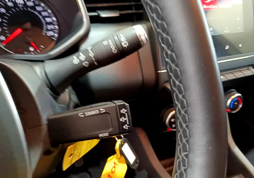 Gros plan sur le volant et commandes de la Renault Clio Business blanche, avec tableau de bord et écran tactile visibles.