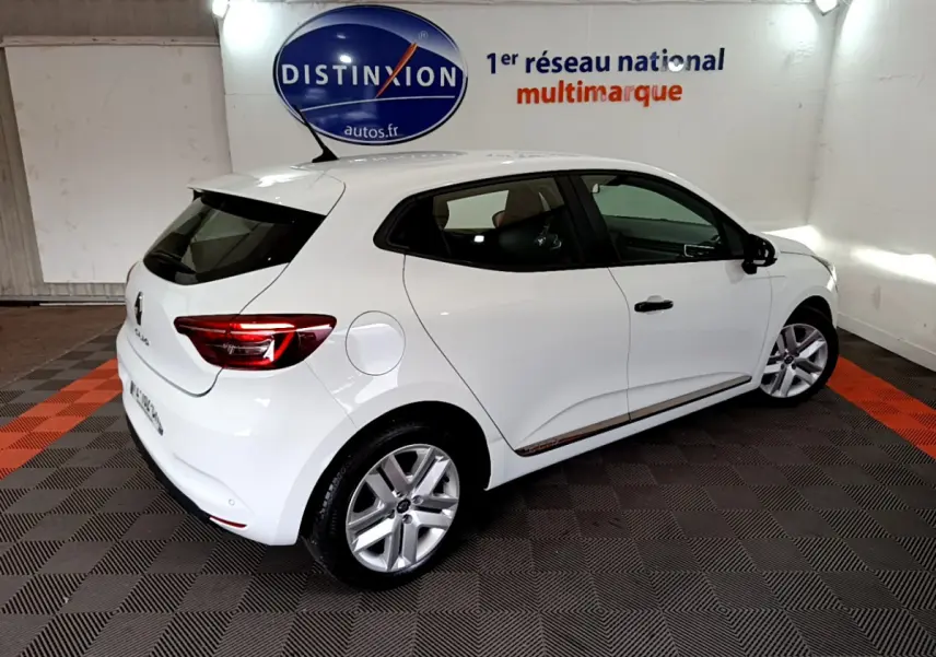 Vue 3/4 arrière droite d'une Renault Clio Business blanche, avec jantes alliage et vitres teintées, en intérieur showroom.