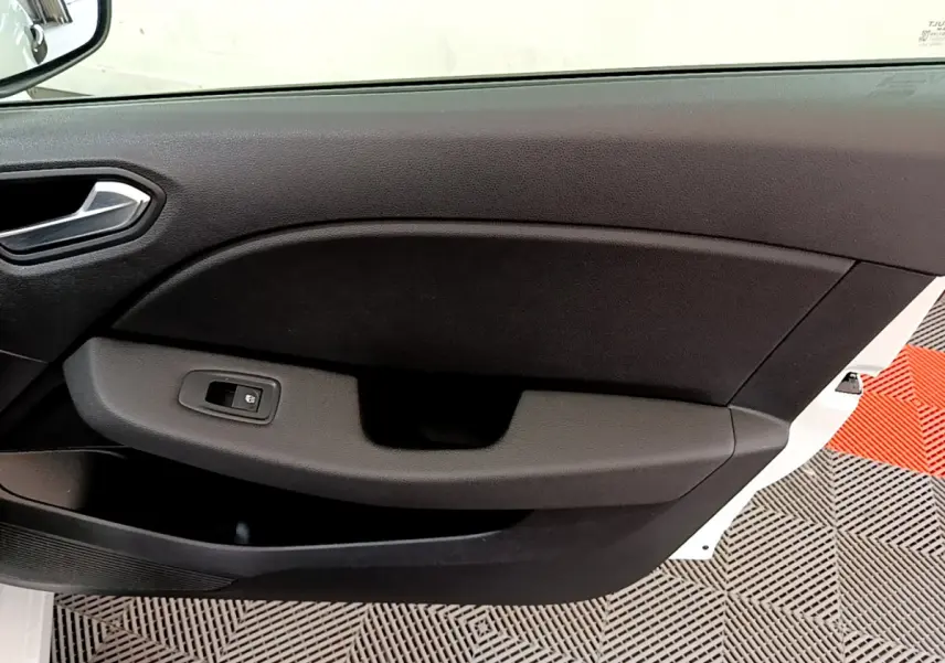 Gros plan sur la porte côté gauche d'une Renault Clio Business blanche, avec commande de vitre électrique noire.