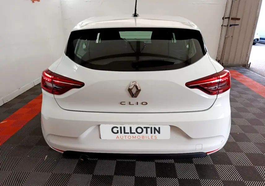 Vue arrière d'une Renault Clio Business blanche 2021 avec feux LED et logo Renault visible sur fond intérieur showroom.