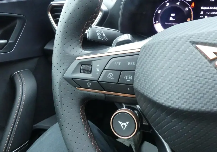 Gros plan sur le volant perforé noir avec surpiqûres cuivrées et commandes multifonctions du CUPRA Formentor gris Graphène 2025.