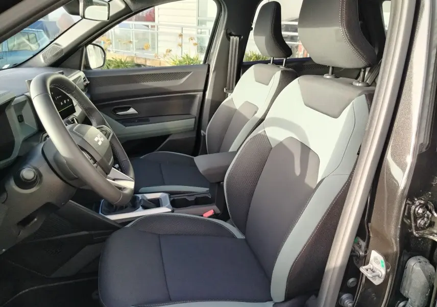 Vue intérieure côté conducteur du Dacia Bigster 2025 noir, montrant les sièges bi-ton et le volant multifonction.