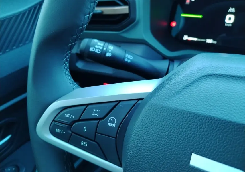 Gros plan sur le volant noir du Dacia Bigster 2025, avec commandes multifonctions et tableau de bord numérique en arrière-plan.