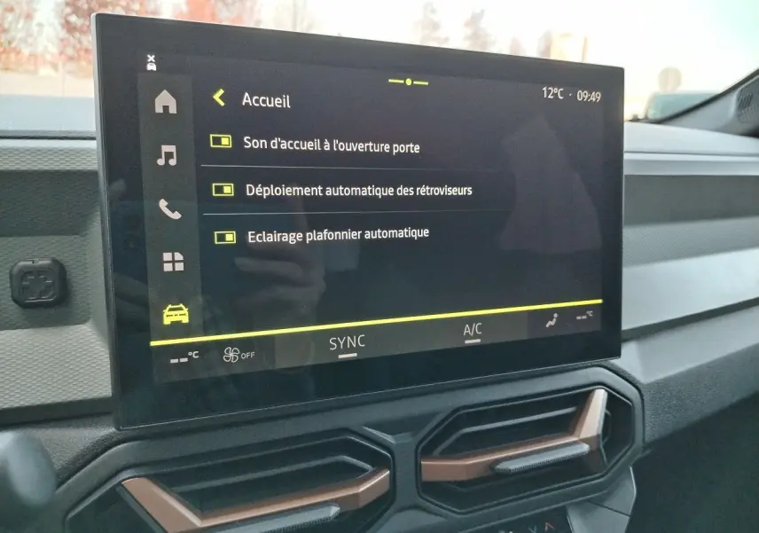 Écran tactile central du tableau de bord du Dacia Bigster 2025 noir, affichant les réglages d'accueil et d'éclairage.