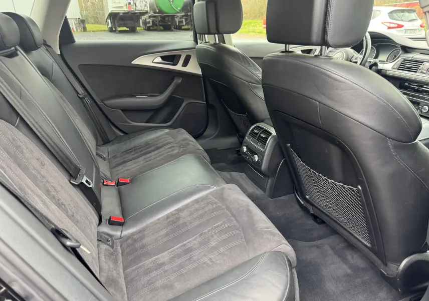 Vue intérieure arrière côté droit de l’Audi A6 Avant 2015 noire, sièges cuir et alcantara avec console de climatisation arrière.