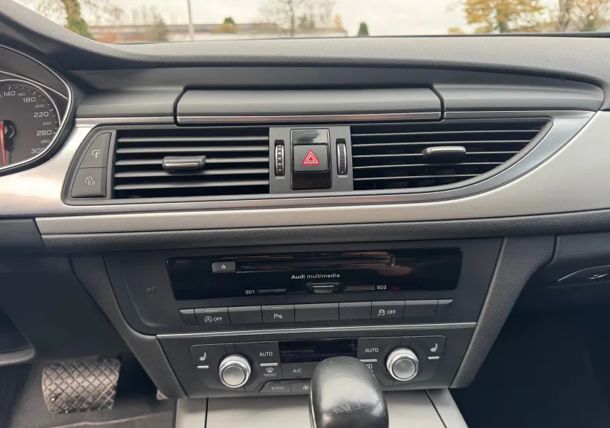 Tableau de bord de l'Audi A6 Avant 2015 noir, vue centrée sur la console avec commandes climatisation et multimédia.
