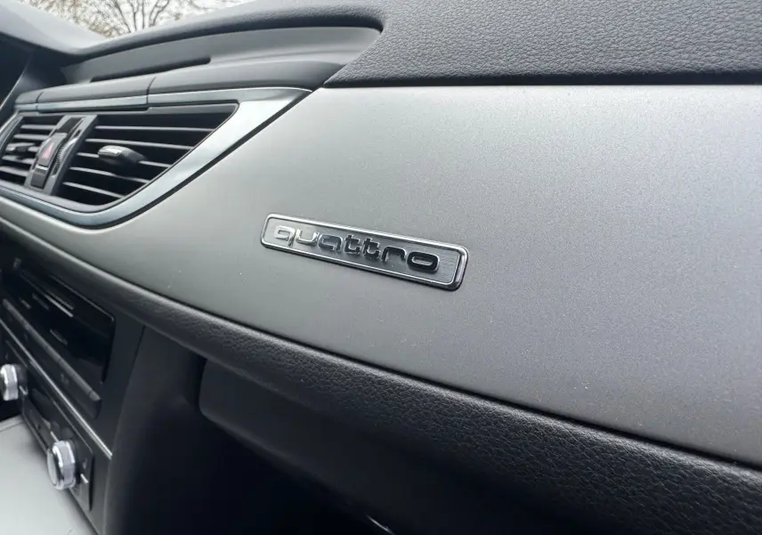 Gros plan sur le tableau de bord gris et noir de l’Audi A6 Avant 2015 avec logo Quattro visible côté passager.