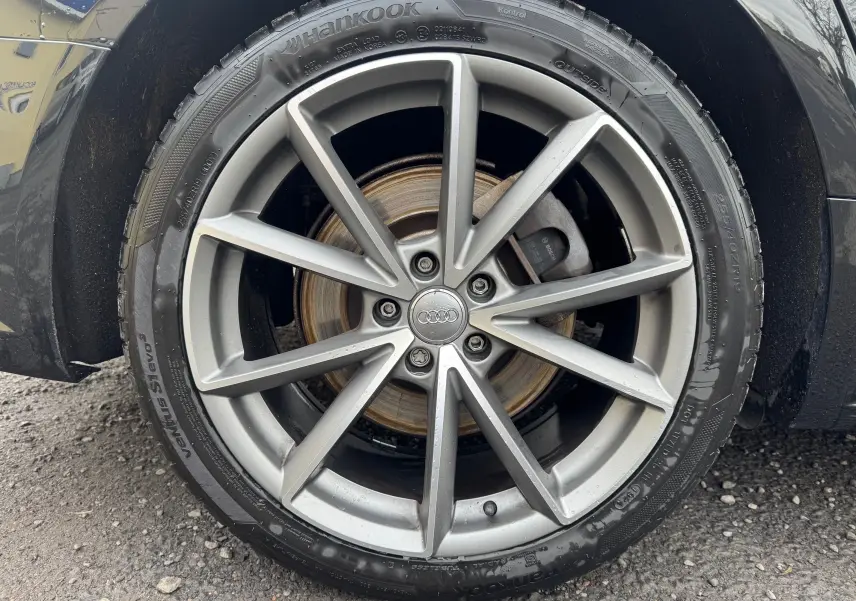 Gros plan sur la jante alliage grise et le pneu Hankook d’une Audi A6 Avant noire, roue avant droite visible.