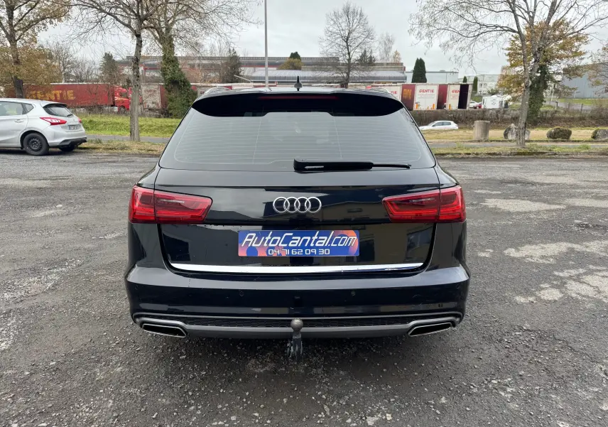 Vue arrière d'une Audi A6 Avant noire de 2015 avec hayon, feux LED et attelage visible sur un parking extérieur.