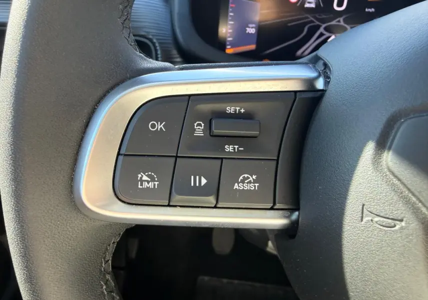 Gros plan sur les commandes du volant à gauche du Jeep Avenger blanc 2025, avec régulateur de vitesse et limiteur.