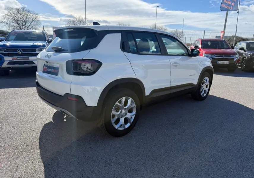 Vue 3/4 arrière droit d’un Jeep Avenger blanc avec jantes alliage 17 pouces, feux arrière fumés et toit noir.