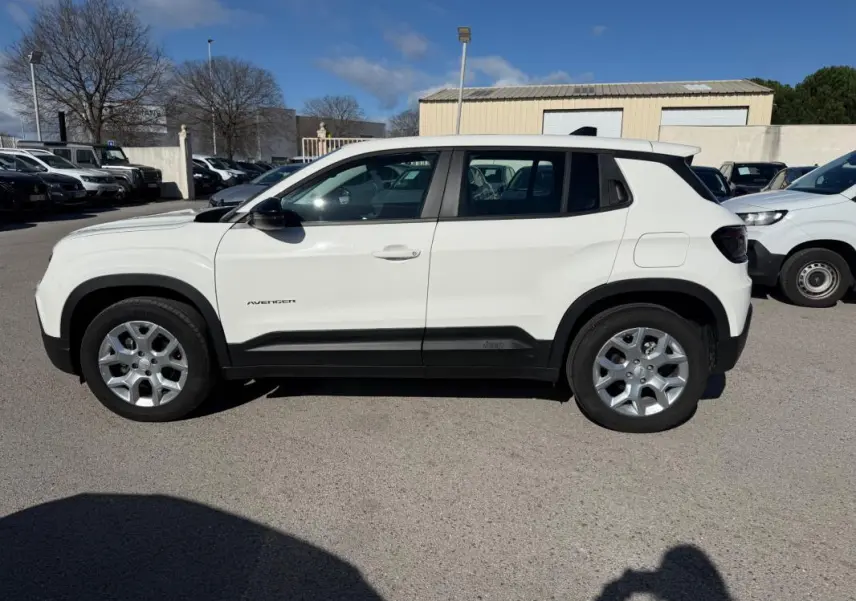 Profil côté gauche d'un Jeep Avenger blanc 2025 avec jantes alliage 17 pouces sur parking extérieur.