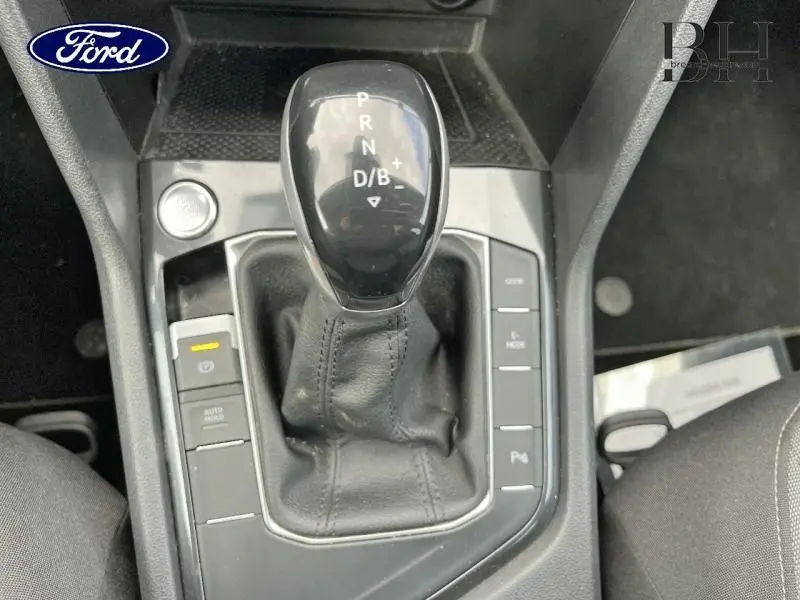 Vue rapprochée du levier de vitesses automatique noir du Volkswagen Tiguan 1.4 eHybrid, entouré de commandes sur console centrale.