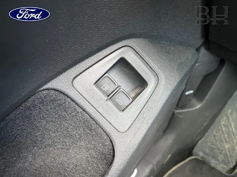 Gros plan sur les boutons d'ouverture de trappe à carburant et coffre, intérieur noir du Volkswagen Tiguan.