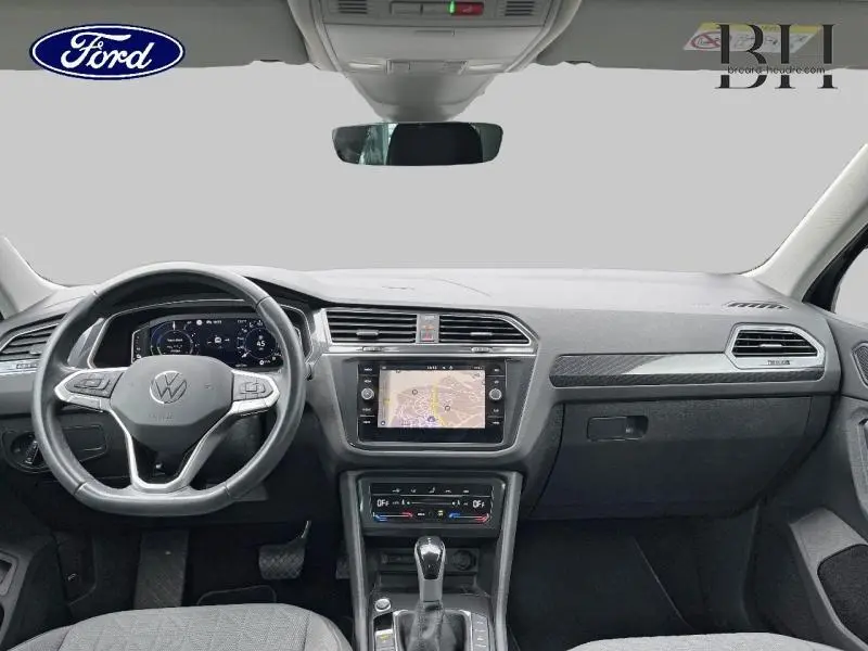 Vue frontale de l'intérieur du Volkswagen Tiguan noir intense nacré, avec tableau de bord et écran tactile central.