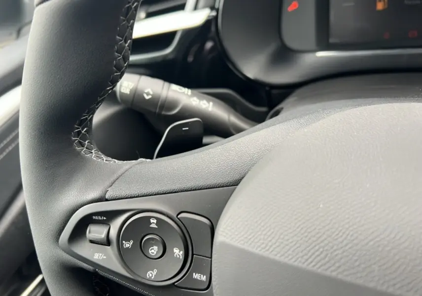 Gros plan sur le volant cuir noir de l’Opel Corsa Hybrid 2026, avec commandes multifonctions et bouton de chauffage.