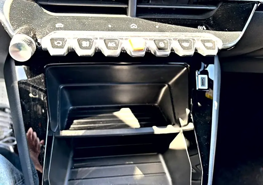 Gros plan sur la console centrale noire brillante du Peugeot 2008 1.2 100 style avec rangements et boutons de commande.