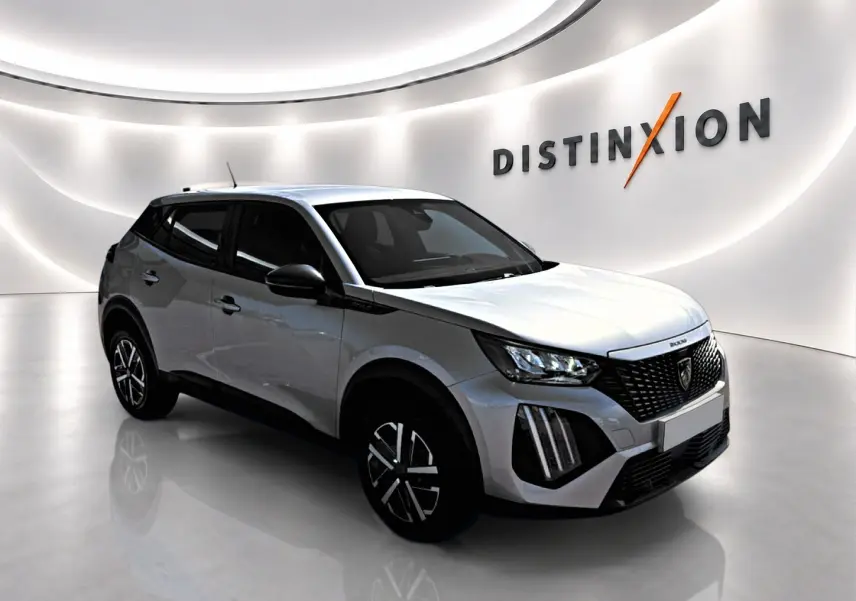 Peugeot 2008 gris 3/4 avant droit en intérieur, avec calandre noire et jantes stylisées noires et argentées.