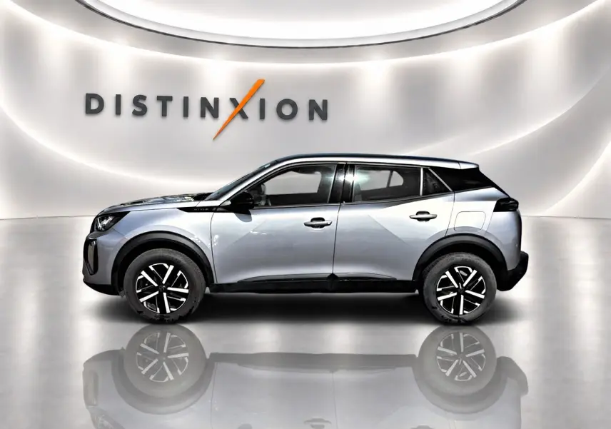 Profil côté gauche du Peugeot 2008 gris 2025 avec jantes noires et toit noir dans un showroom lumineux.