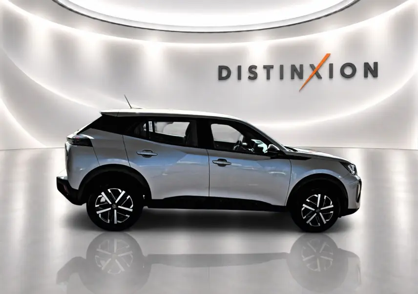 Peugeot 2008 gris en profil droit dans un showroom lumineux avec toit noir et jantes distinctives.