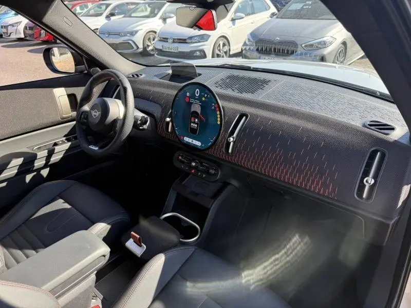Vue intérieure avant droite du MINI Countryman argenté 2025, tableau de bord avec écran circulaire digital et volant multifonction.