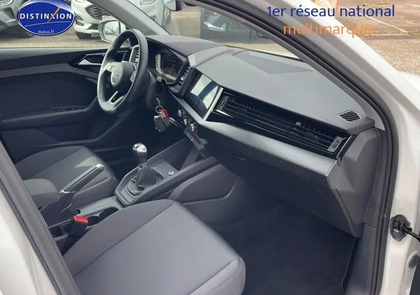 Intérieur avant droit d'une Audi A1 Sportback blanche 2022, volant cuir sport et boîte manuelle visible.