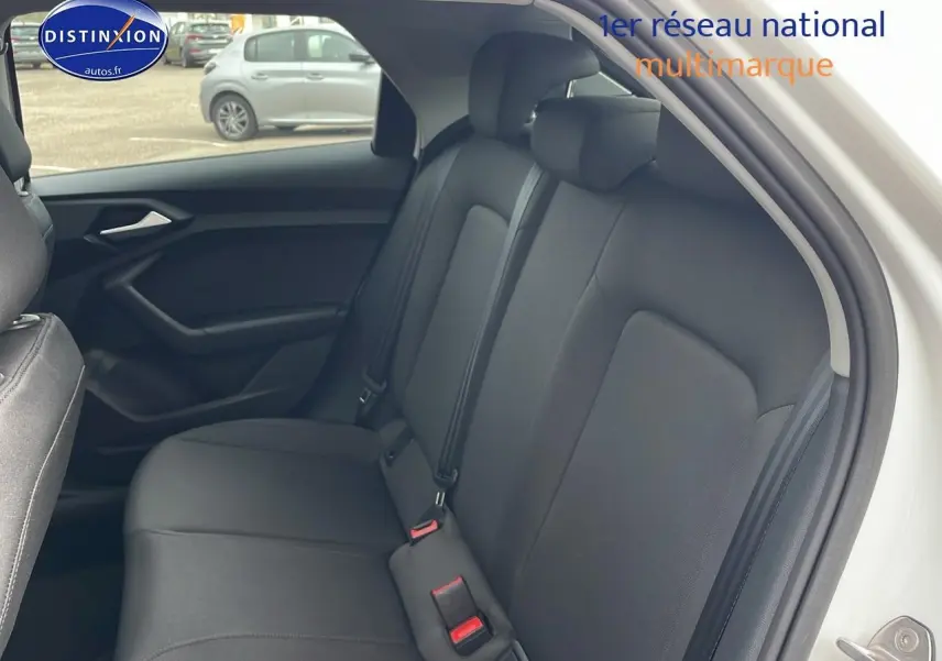 Vue intérieure sur la banquette arrière noire de l'Audi A1 Sportback blanche, côté droit avec appuie-têtes et ceintures visibles.
