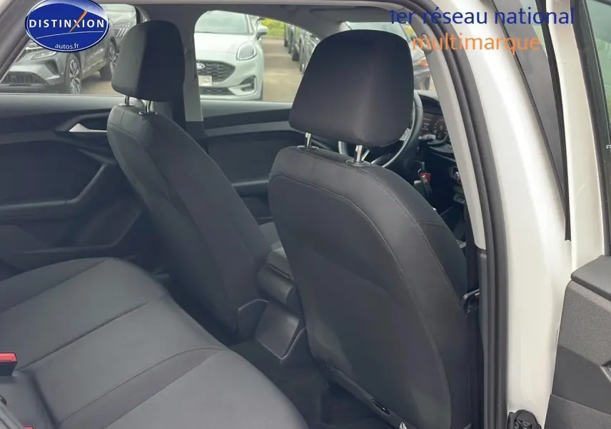 Intérieur arrière de l'Audi A1 Sportback blanc, montrant les sièges noirs et l'ouverture de la porte côté droit.