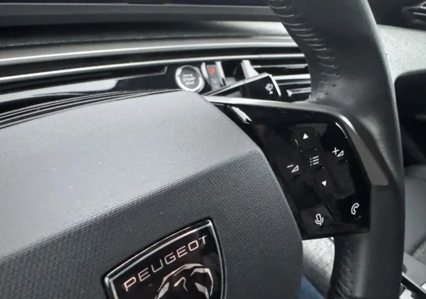 Gros plan sur le volant noir du Peugeot 3008 Hybrid 145 e-DCS6 Allure 2025 avec commandes tactiles intégrées.
