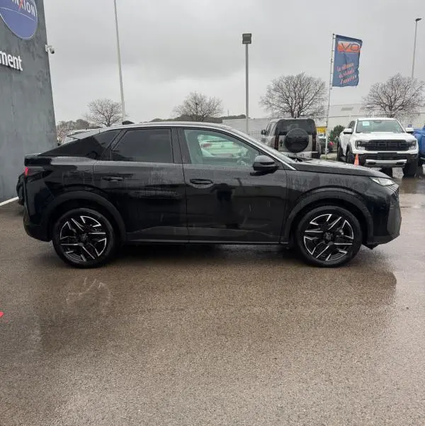 Vue de profil côté gauche d'un Peugeot 3008 Hybrid 145 Allure noir avec jantes alliage 19 pouces sous un ciel gris.