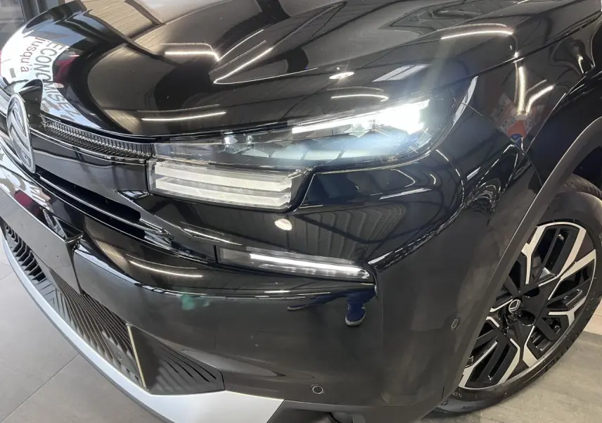 Vue 3/4 avant droit d'une Citroën C4 noire métallisée avec phares LED et jantes alliage 18 pouces.