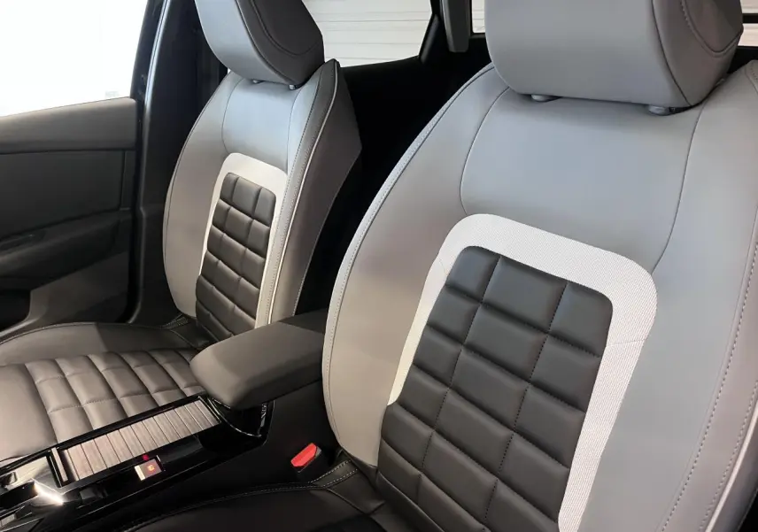 Gros plan sur les sièges avant gris clair et noir avec accoudoir central de la Citroën C4 2025.