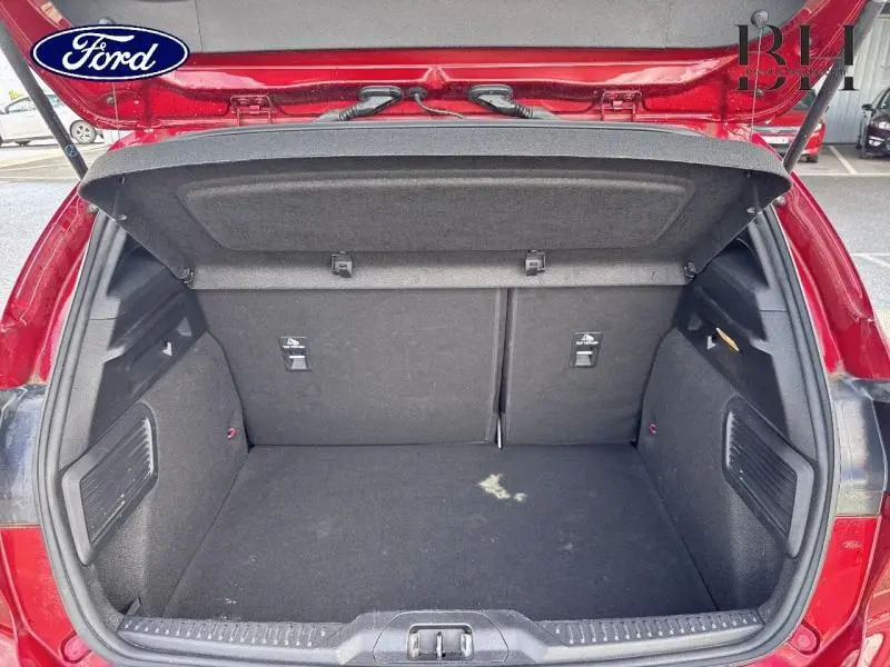 Coffre ouvert vu de l'arrière d'une Ford Focus 1.0 EcoBoost 125ch rouge Premium Candy, intérieur noir.