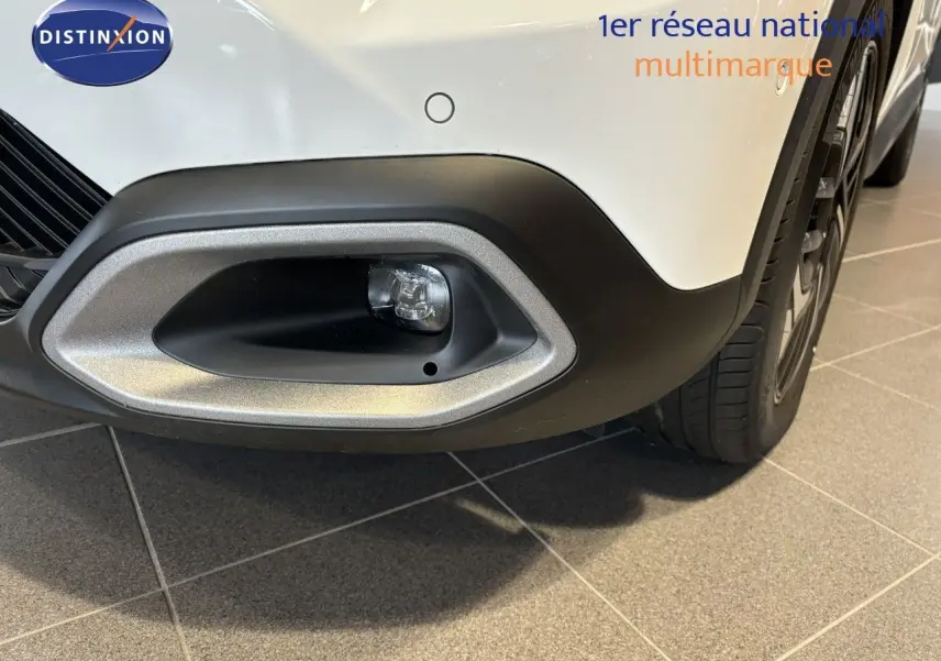 Gros plan sur l'antibrouillard avant droit du Citroën C4 blanc 2022 avec pare-chocs noir et jante visible.