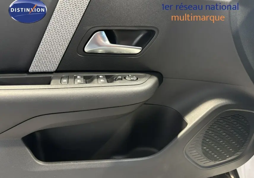 Intérieur de la porte côté gauche d'une Citroën C4 blanche 2022, avec commandes de vitres et poignée argentée.