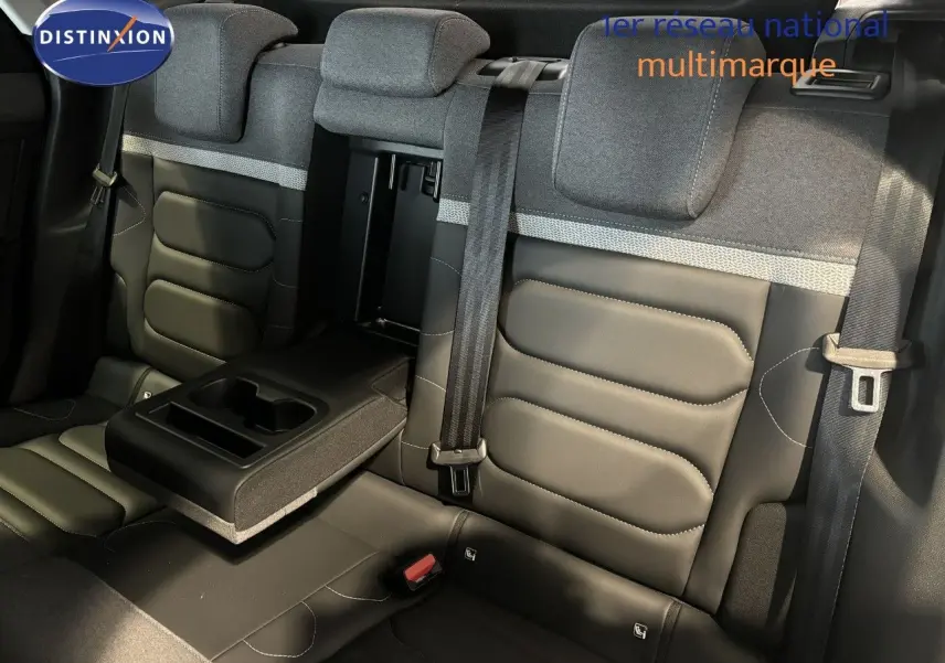 Vue intérieure arrière des sièges en tissu et cuir noir du Citroën C4 2022 avec accoudoir central relevé et ceintures visibles.