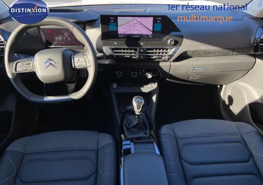 Vue intérieure avant de la Citroën C4 blanche 2022, avec tableau de bord moderne et levier de vitesses manuel.