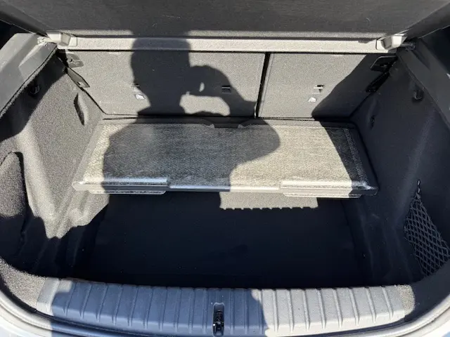 Coffre ouvert de BMW Série 1 118d gris foncé, montrant le plancher modulable et les parois intérieures en tissu noir.