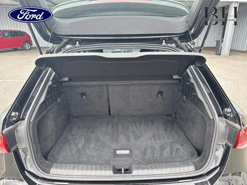 Coffre ouvert vu de l'arrière d'une Audi A3 Sportback 35 TDI noir Mythic métallisé, espace de chargement vide et propre.