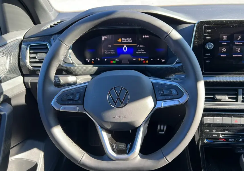 Vue rapprochée du volant cuir multifonctions et du tableau de bord numérique du Volkswagen T-Cross blanc pur 2025.