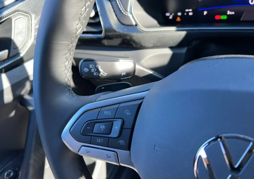 Gros plan sur le volant cuir multifonctions côté gauche du Volkswagen T-Cross blanc pur avec commandes de régulateur de vitesse.