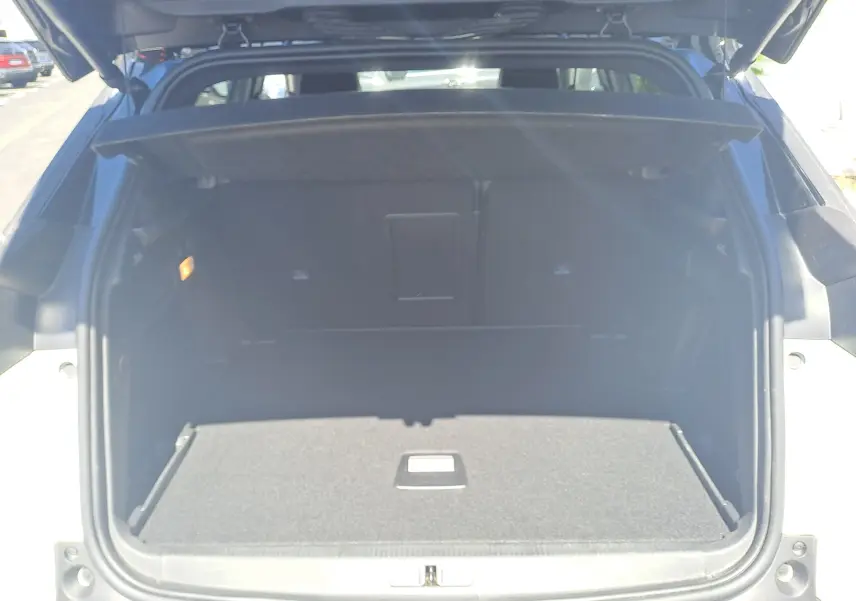 Coffre ouvert vu de l'arrière d'un Peugeot 3008 blanc nacré avec toit noir, montrant un espace de chargement vide.