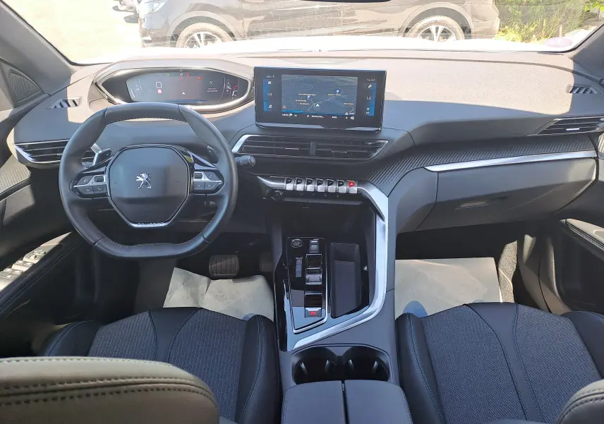Vue intérieure avant du Peugeot 3008 2023, tableau de bord moderne avec écran central tactile et volant compact noir.
